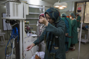 A woman holds a bag of blood in the air, preparing it for a transfusion