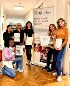 Group of women at an event – A group of women posing in front of a banner at an event.