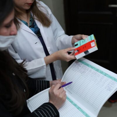 Two doctors in Pakistan consider a patient's chart and hold a packet of tranexamic acid.