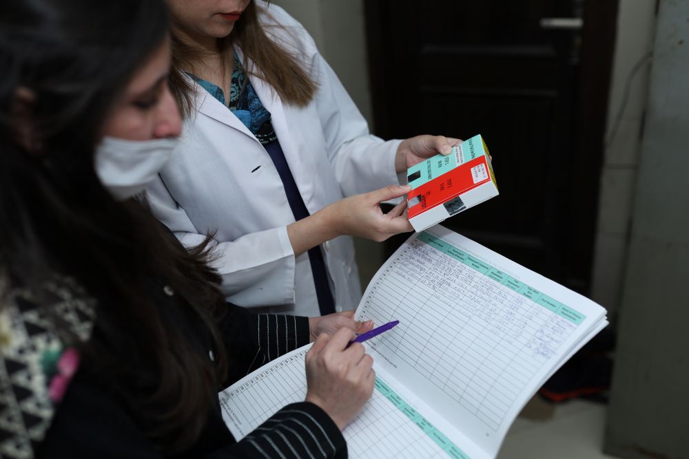 Two doctors in Pakistan consider a patient's chart and hold a packet of tranexamic acid.