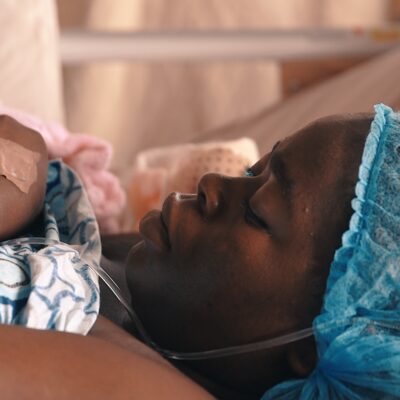 Close up of a woman lying in a hospital bed on a maternity ward. She had a canula in her hand.