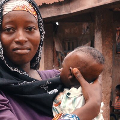 A woman holds a baby close to her chest.